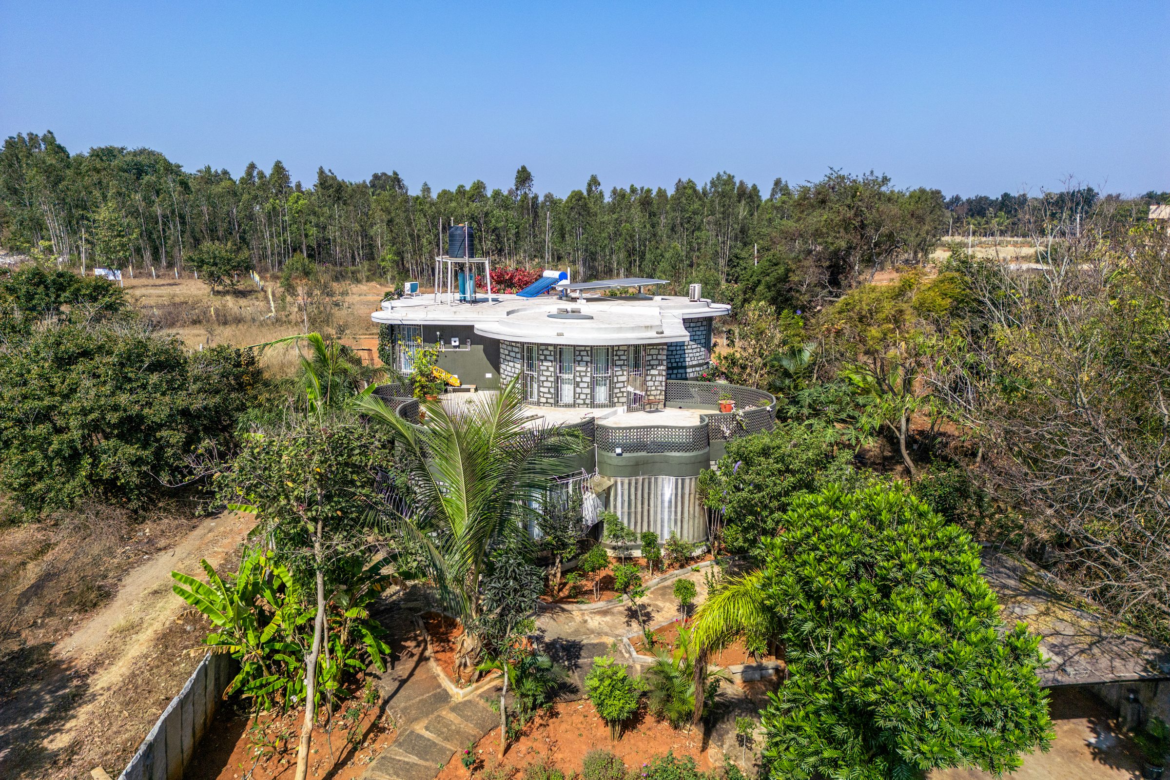 Aerial view of the curved-stone villa surrounded by trees