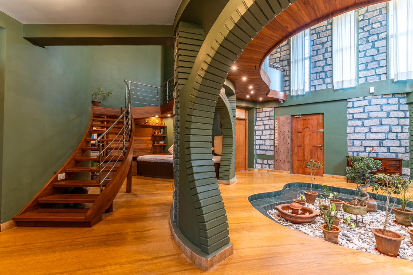Curved stone archway framing the sunken indoor courtyard garden and spiral staircase at the center of Brahmasthanam