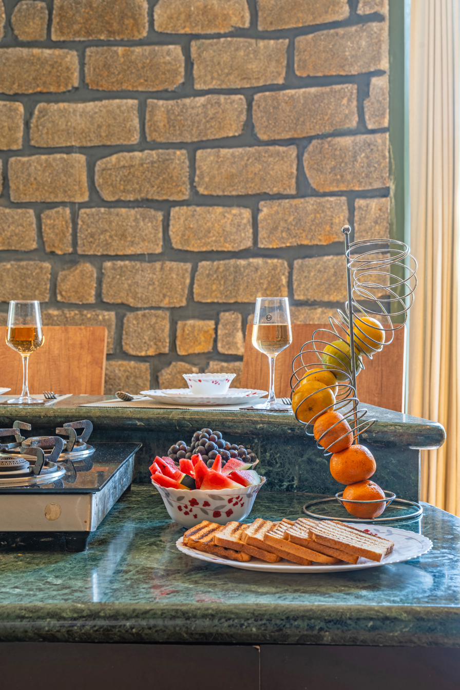 Breakfast spread of toast, fruit and juice on a green marble countertop against a stone wall