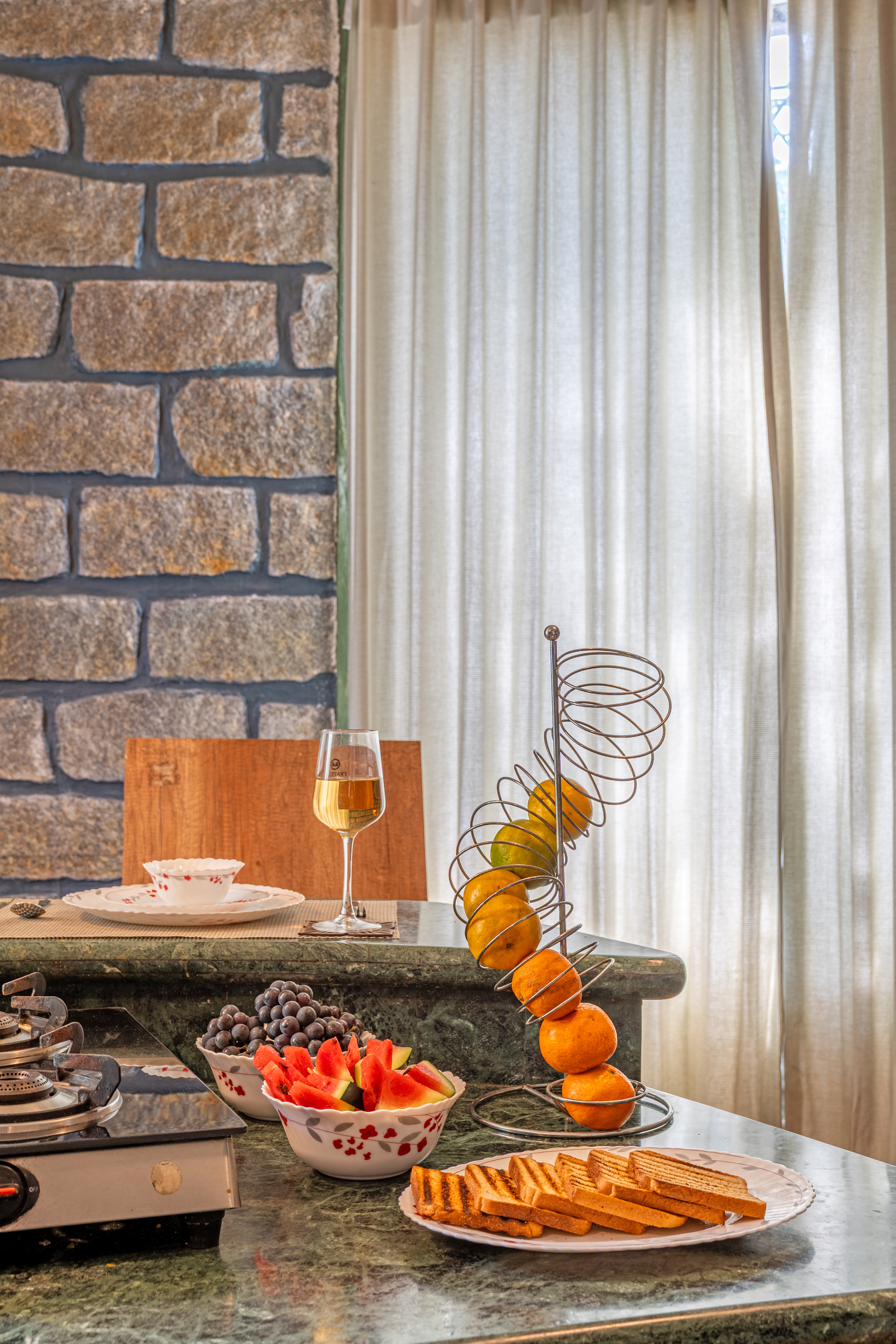 Wide view of the dining spread with fresh fruit, toast and a spiral fruit stand against the stone wall