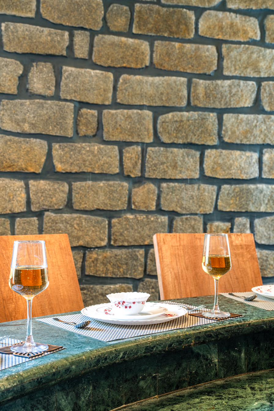 Table setting with two wine glasses against a curved stone wall