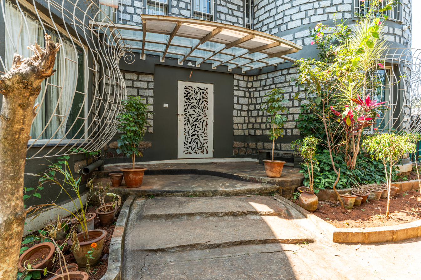 Curved stone entrance facade with a laser-cut leaf pattern door