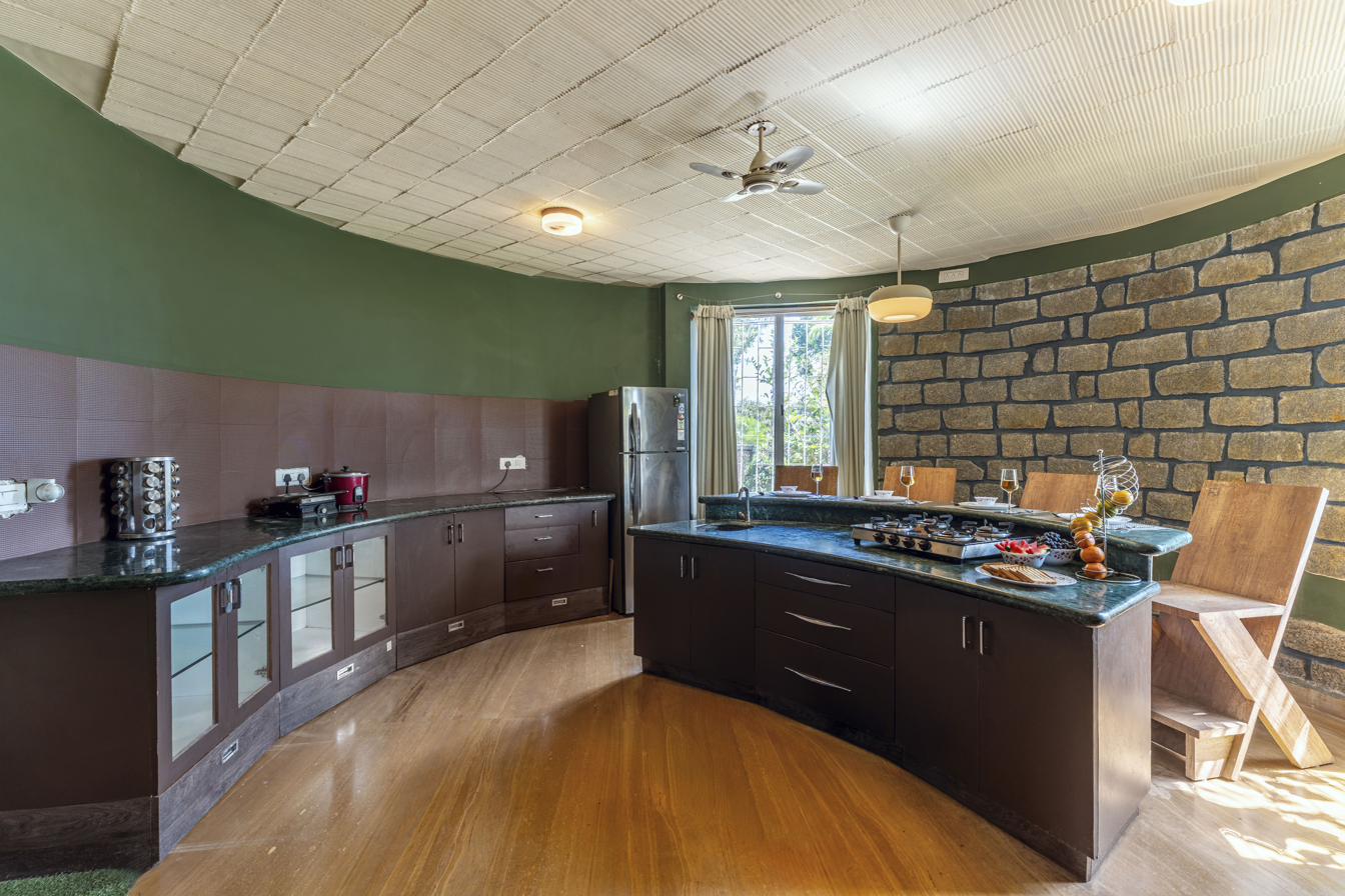 Curved kitchen with dark cabinetry, green marble countertop and stone accent wall