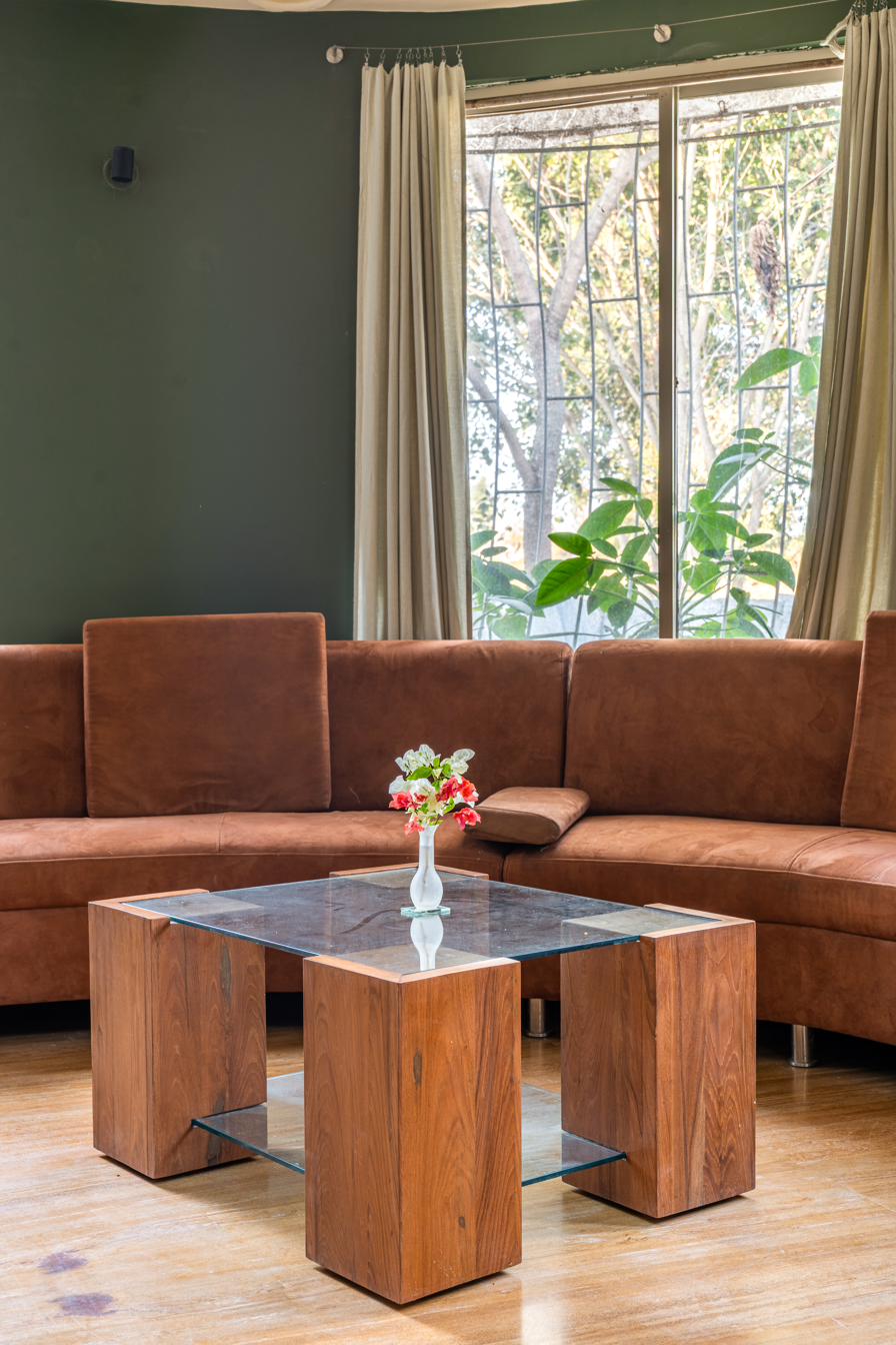Wooden coffee table with fresh flowers in front of a curved suede sofa