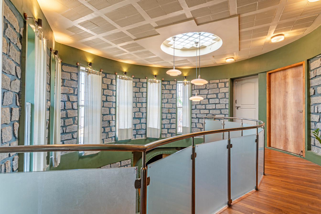 Upstairs mezzanine landing with round skylight, stone walls and glass railing