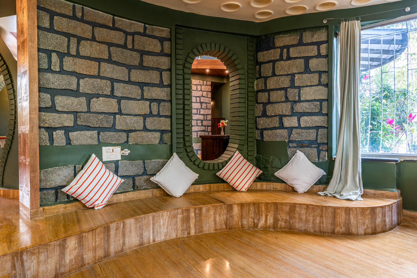 Curved stone-walled seating nook with cushions and an oval mirror