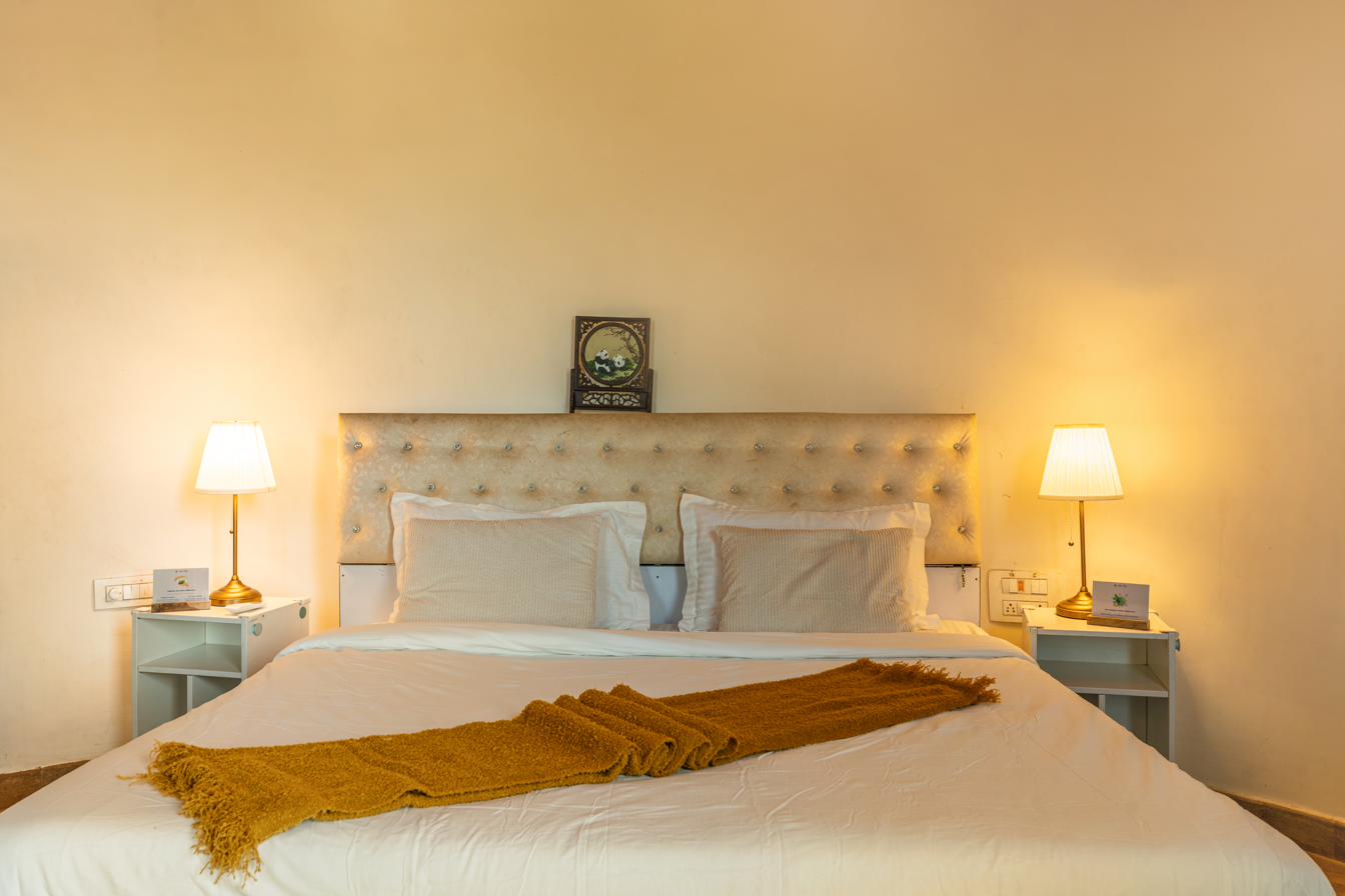 Bedroom in warm ivory tones with tufted headboard and brass lamps