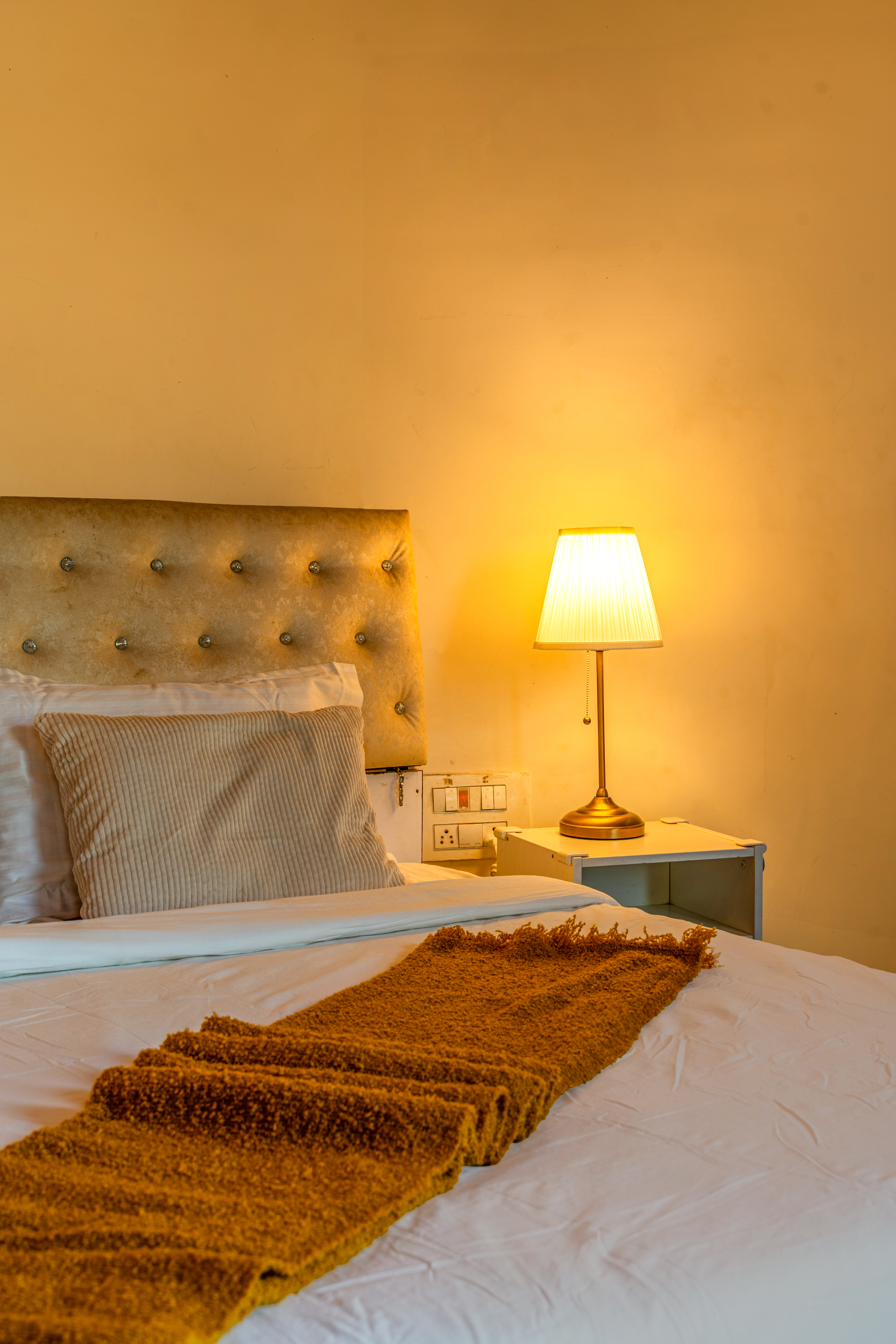 Bedside lamp glowing warmly, mustard throw folded on the bed
