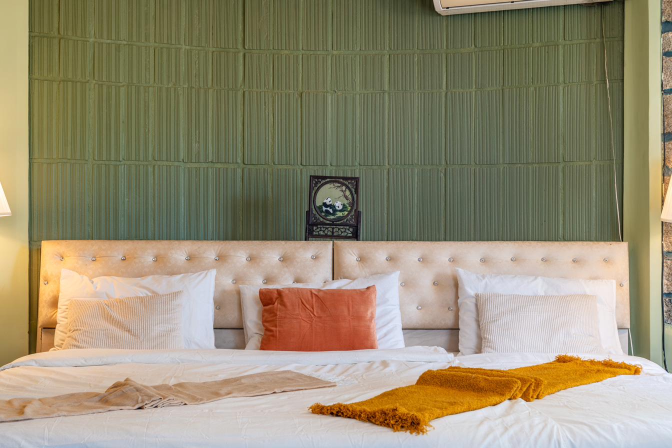 Bedroom with sage green ribbed wall panels, cream tufted headboard and a small framed painting