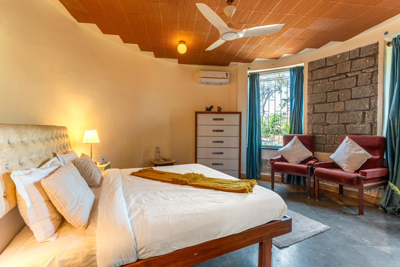 Bedroom with wood-slat curved ceiling, teal curtains and dark stone accent wall